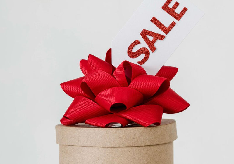 little gift box with sale tag on it and red bow