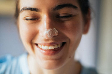 woman smiling with face cream on nose