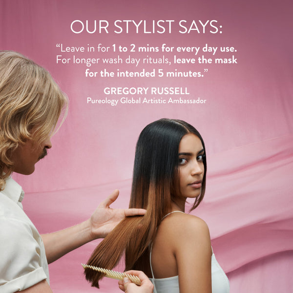 A promotional beauty graphic with pink background and text reading 'OUR STYLIST SAYS:' followed by a quote attributed to Gregory Russell, Pureology Global Artistic Ambassador. A stylist is shown from the side grooming a model with long dark-to-brown ombre hair, while the model looks over her shoulder.