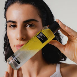 Woman holding a bottle of hair care product against her hair
