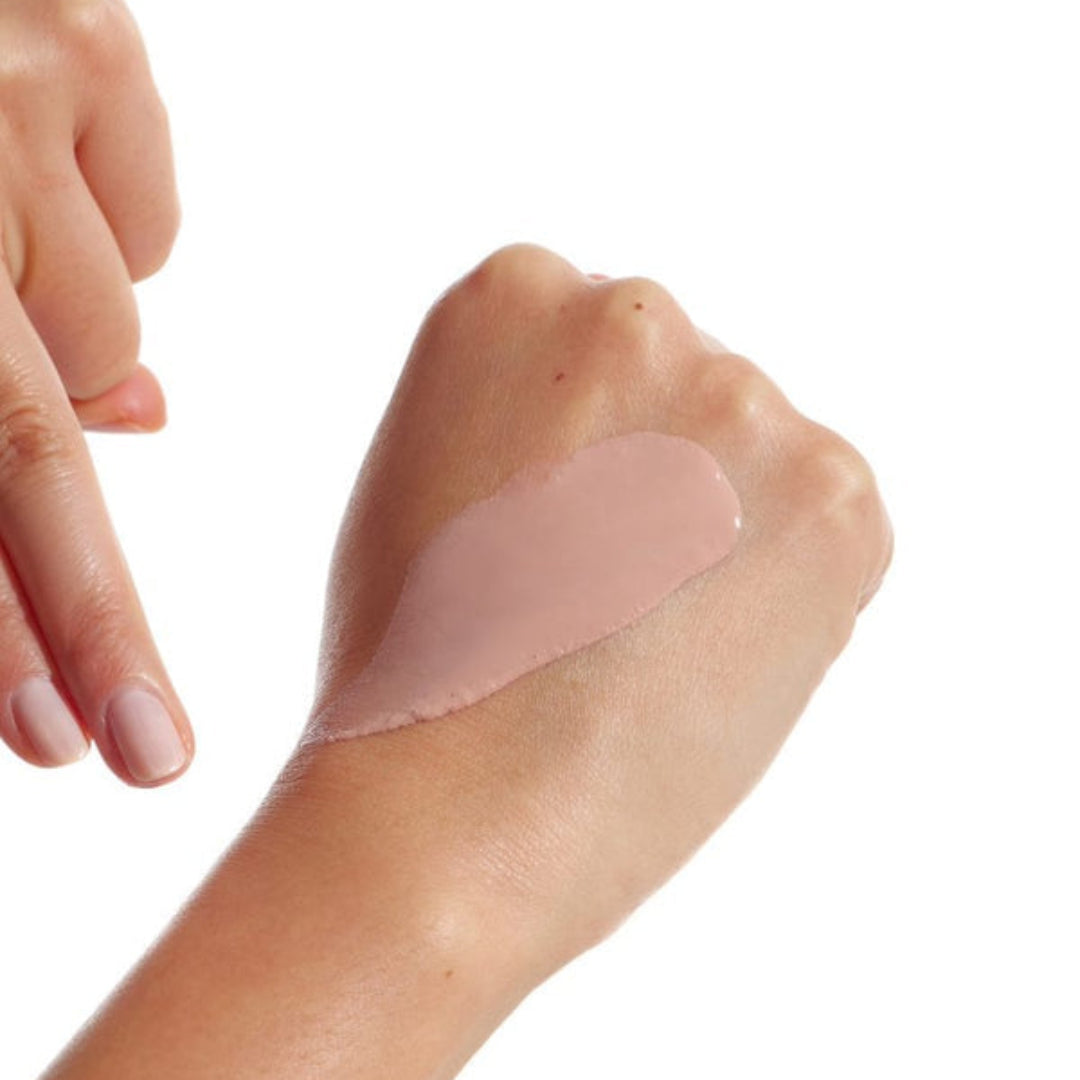 Person applying a beige adhesive patch on their wrist with a white background
