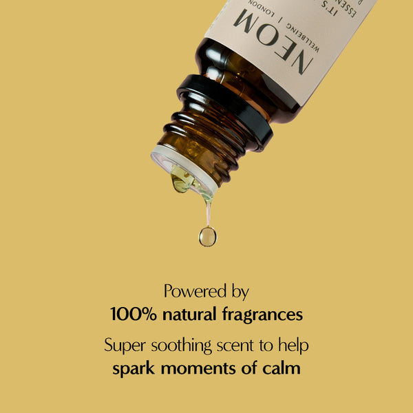 Bottle of NEOM essential oil with a droplet on a beige background