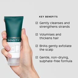 Hand holding a Philip Kingsley Density product with key benefits listed on a light gray background