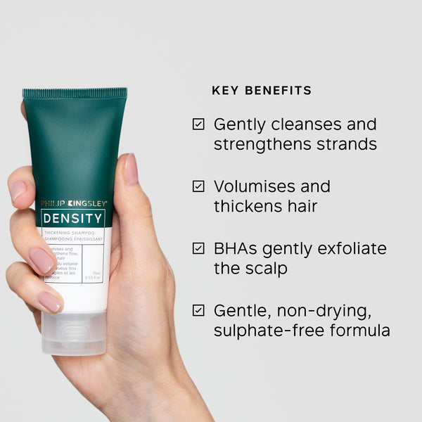 Hand holding a Philip Kingsley Density product with key benefits listed on a light gray background