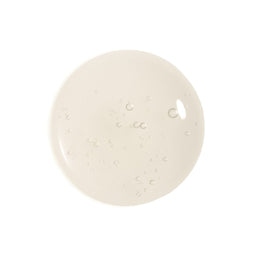 A circular swatch of translucent, slightly glossy cream-colored gel or liquid with small air bubbles, centered on a solid white background.