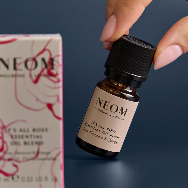 NEOM essential oil bottle held by a hand with a NEOM box in the background