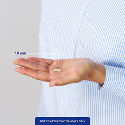 Hand holding a capsule with measurement label and text on a plain background