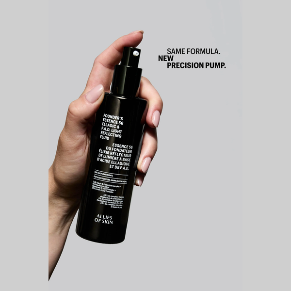 A hand holding a black bottle of Allies of Skin Founder's Essence 24 Hour & Night Moisturizing Fluid against a light gray background, with text on the right reading 'SAME FORMULA. NEW PRECISION PUMP.