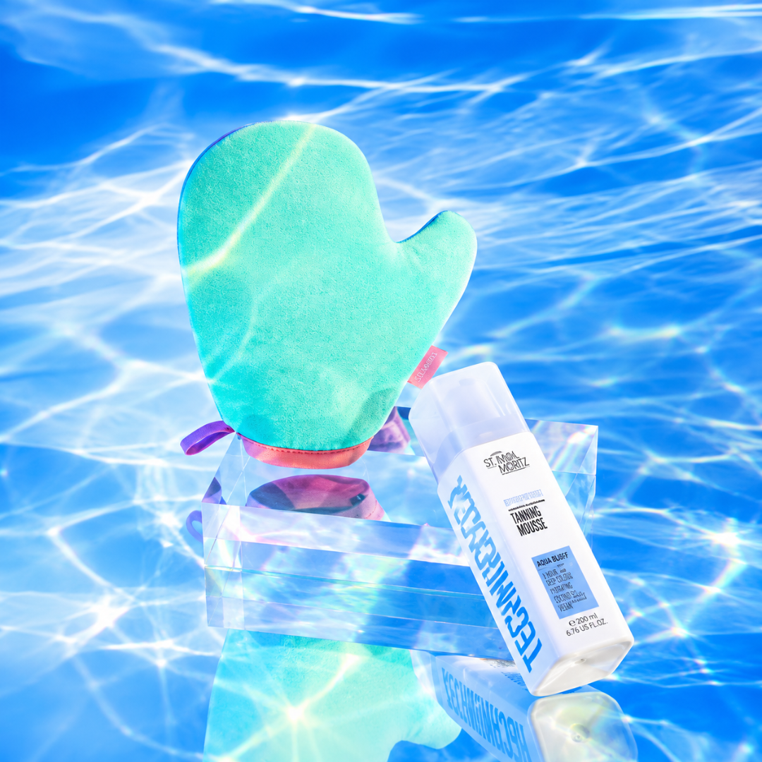A teal and pink silicone pool float with a built-in bottle holder, shown floating on blue water with sunlight ripples. A white TechnoCheekers sunscreen bottle is resting inside the float.
