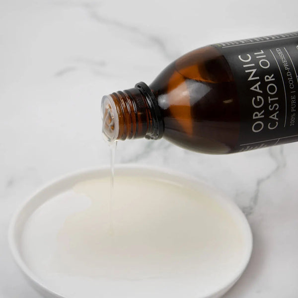Bottle of Organic Oil being poured into a bowl on a marble surface