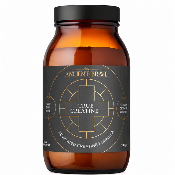 An amber glass supplement jar with a black lid and a black label featuring gold text and a geometric cross design. The label reads 'ANCIENT+BRAVE' and 'TRUE CREATINE+'.