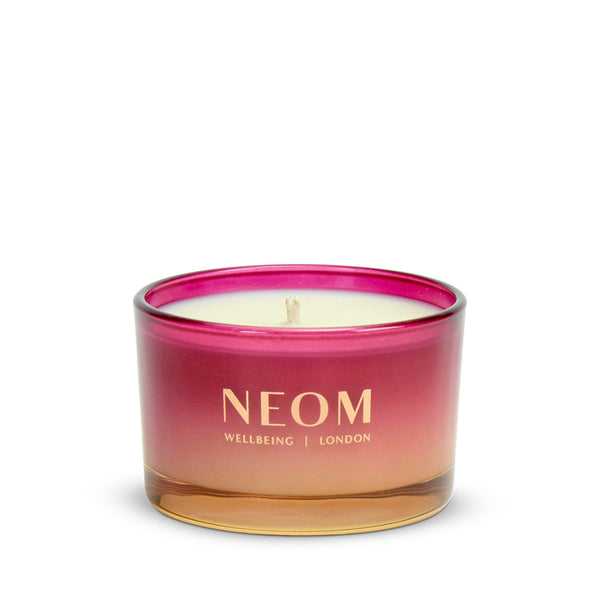 Neom candle with pink and gold design on a white background