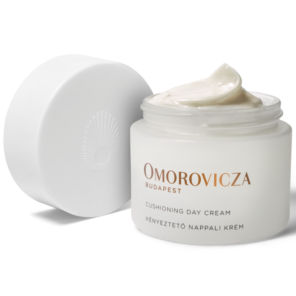 Omorovicza Cushioning Day Cream in a white jar with its lid off, showing a dollop of the cream on top, on a white background.