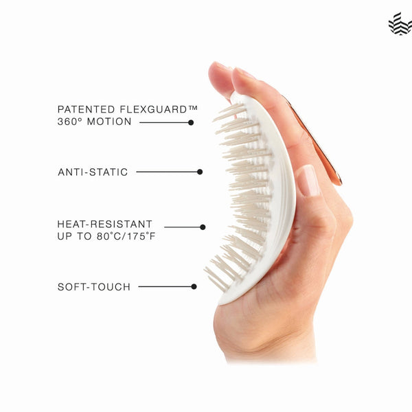 A hand holds a white oval hairbrush with soft bristles against a clean white background, with text callouts reading 'PATENTED FLEXGUARD 360° MOTION,' 'ANTI-STATIC,' 'HEAT-RESISTANT UP TO 80°C/175°F,' and 'SOFT-TOUCH.'.