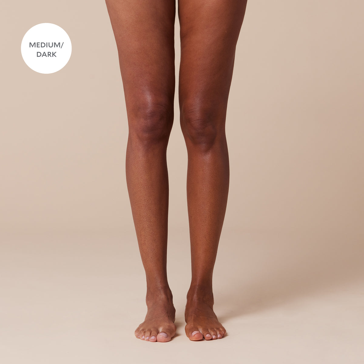 Legs wearing medium-dark tights against a beige background