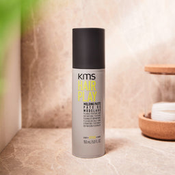 KMS Hair Play molding paste bottle on a neutral background