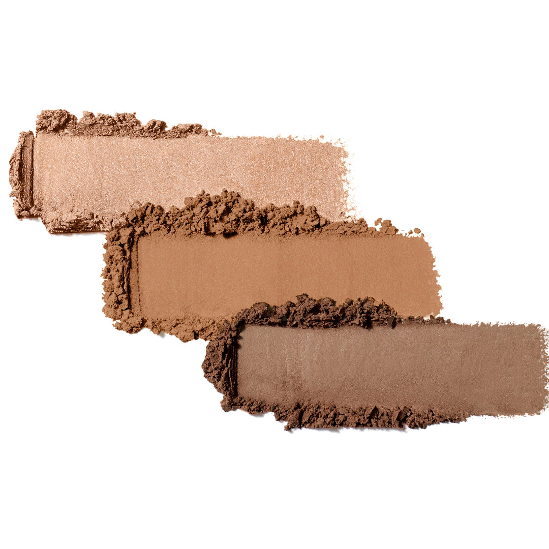 Three swatches of brown makeup product on a white background