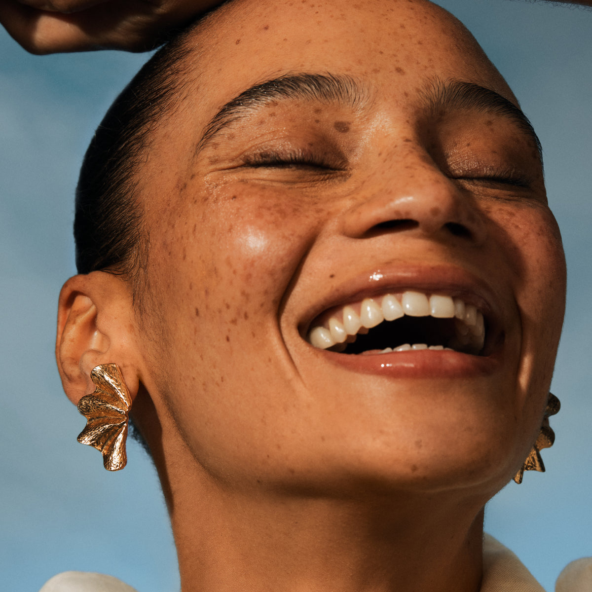 Close-up of a person with a bright smile against a clear blue sky