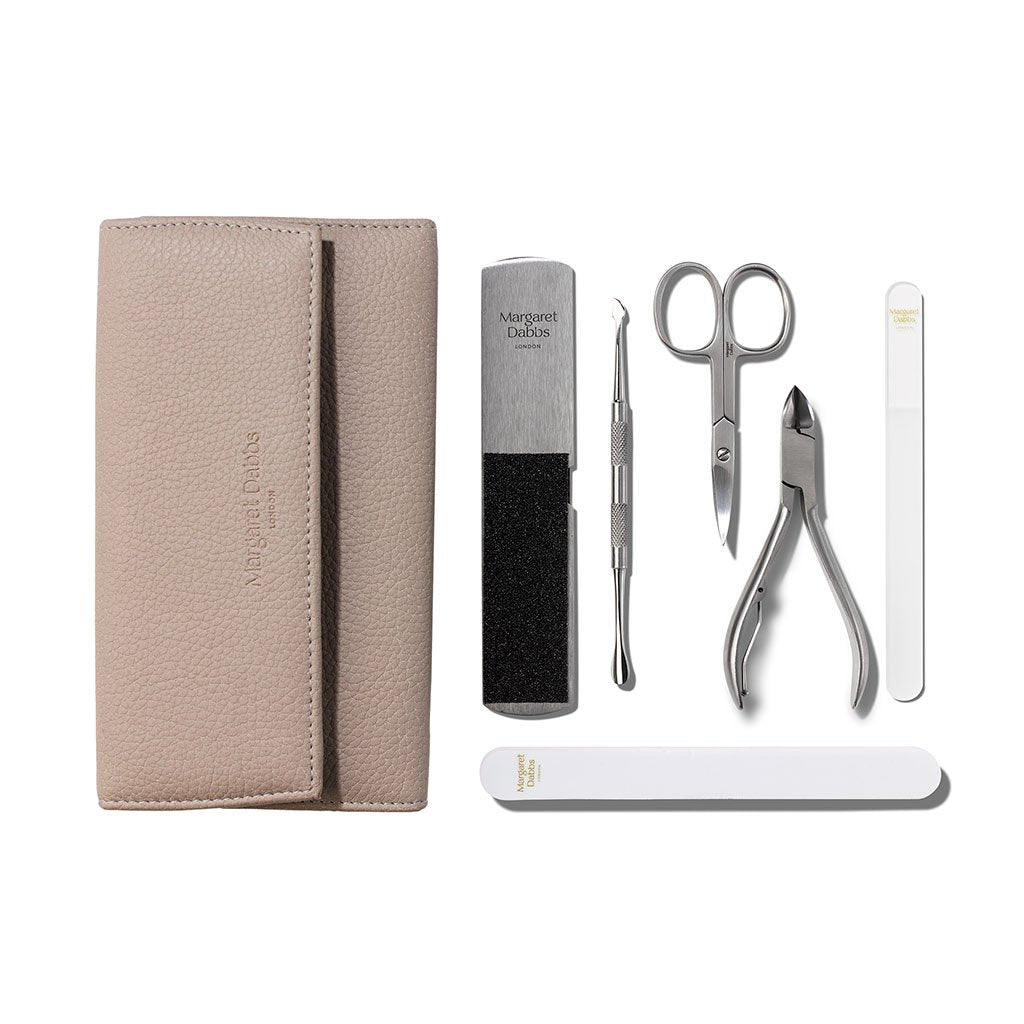 Manicure set with beige case, scissors, cuticle nipper, and other tools on a white background