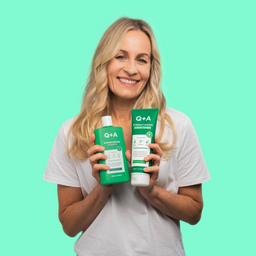 Woman holding Q+A hair care products against a green background