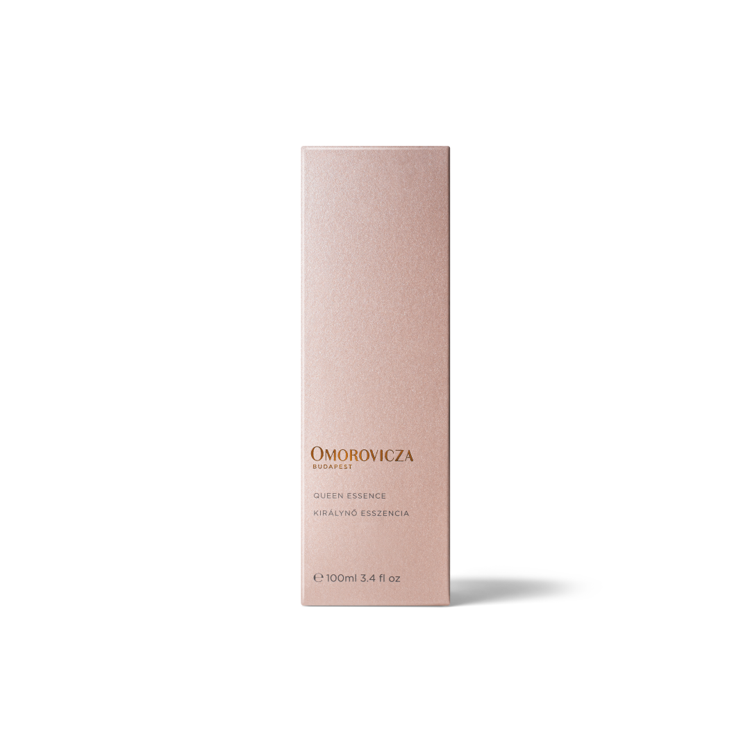 A tall, slim rectangular box for Omorovicza Queen Essence in a pale blush pink color with gold lettering, set against a clean white background.