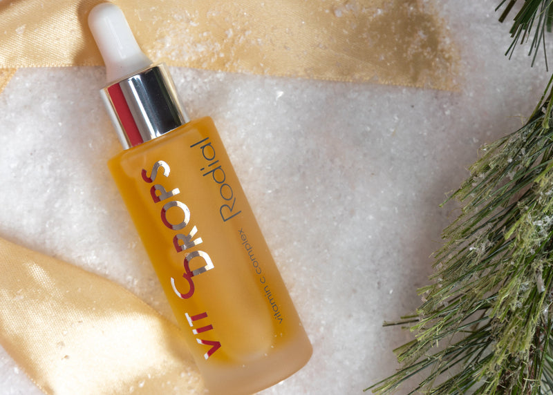 Skincare serum bottle with greenery on a textured surface