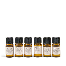Set of six NEOM essential oil bottles on a white background