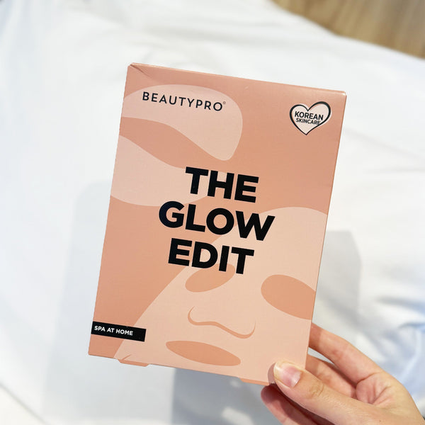A hand holding a Beautypro 'The Glow Edit' SPA at home box against a soft white background.