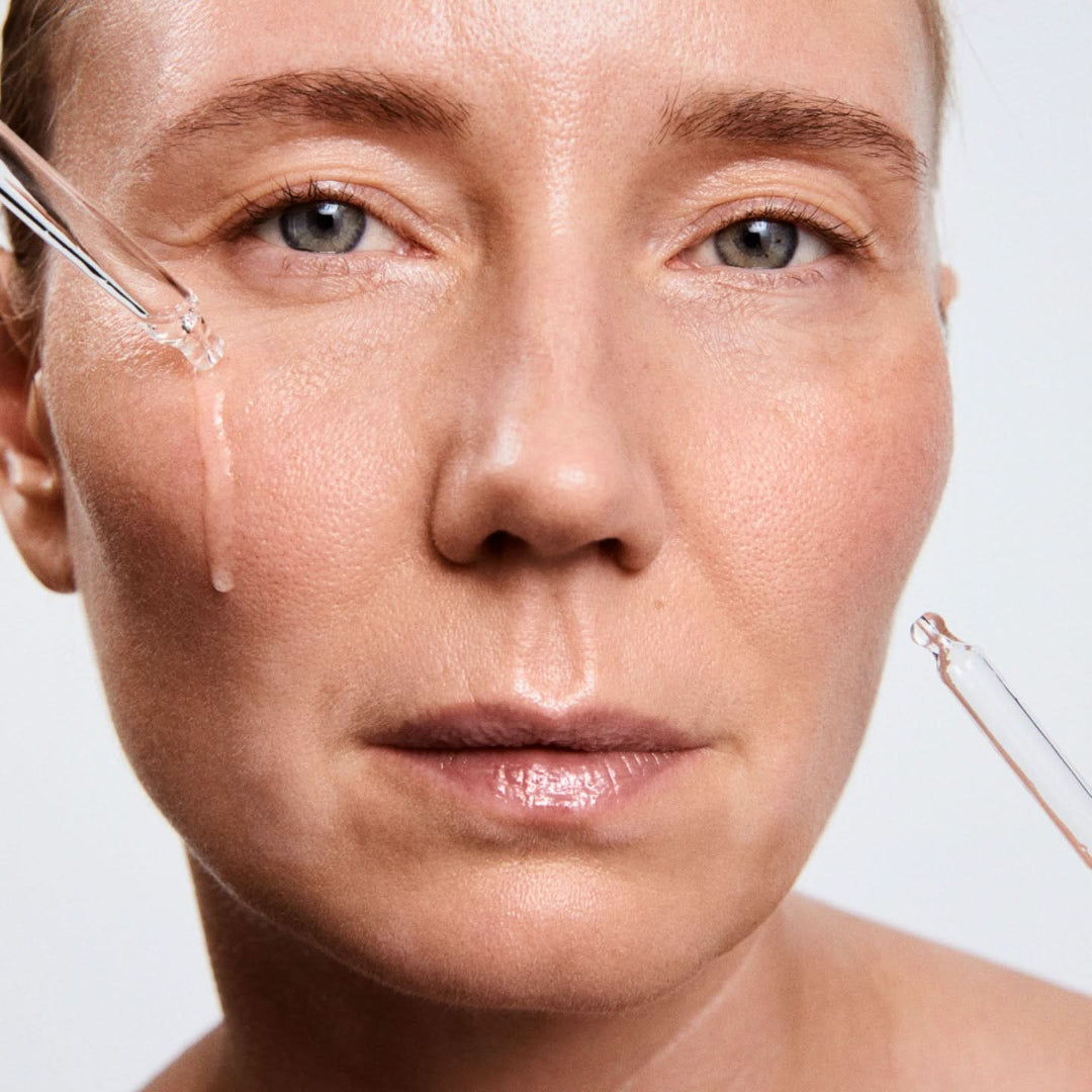 Close-up of a woman's face with a skincare tool on a neutral background