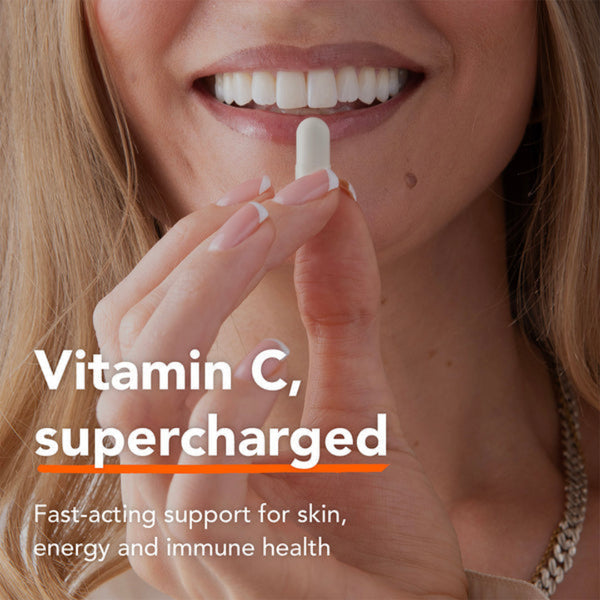 Close-up of a smiling woman holding a white vitamin supplement tablet near her mouth, with text reading 'Vitamin C, supercharged' and 'Fast-acting support for skin, energy and immune health'.