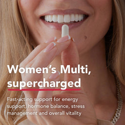 Close-up of a smiling woman holding a white capsule pill near her mouth, with text reading 'Women's Multi, supercharged' and additional product copy about energy, hormone balance, stress management, and overall vitality.