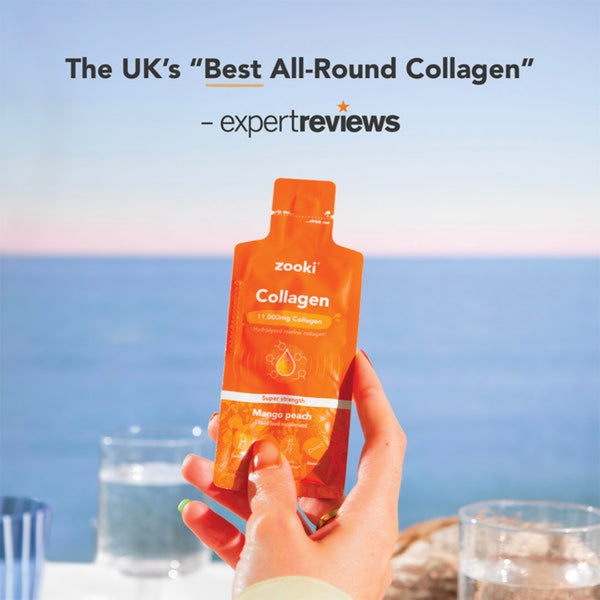 A hand holding a Zooki Collagen liquid supplement pouch in orange packaging, with a blurred ocean background and text at the top reading 'The UK's Best All-Round Collagen - expertreviews'.