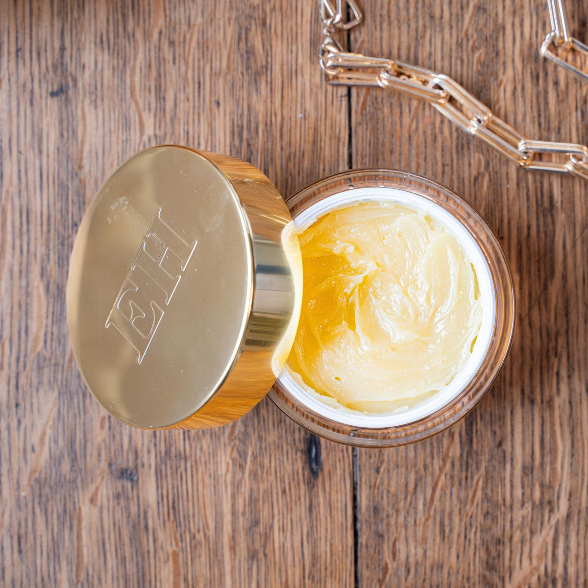 Open jar of of Emma Hardie Vit C Brilliance Cleansing balm showing product texture on a wooden surface