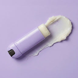 White grooming tool with cream on a purple background