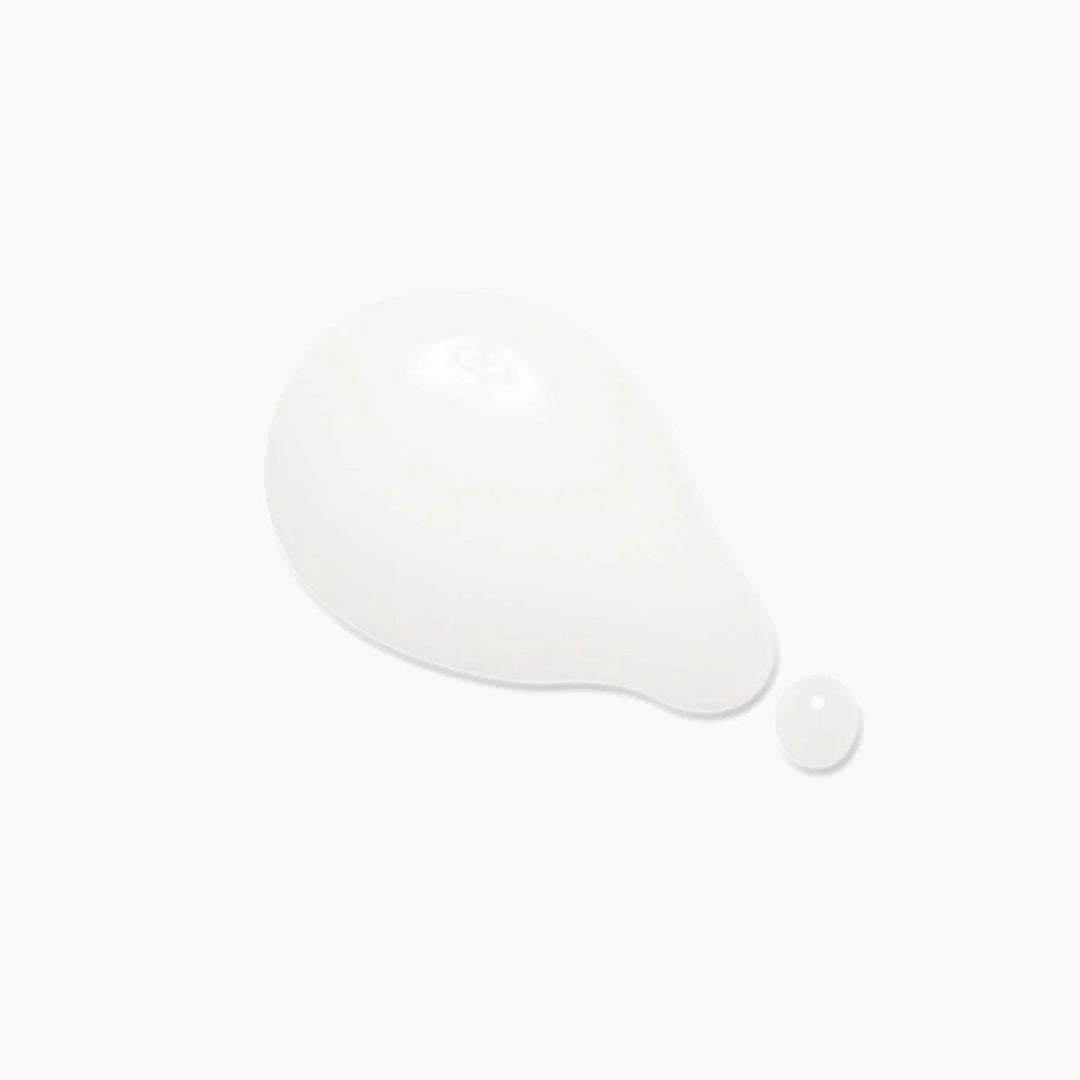 A glossy white teardrop-shaped droplet of cream or serum with a small separate droplet beside it, centered on a very light off-white background.