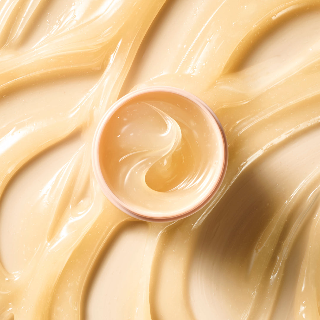 Close-up of a container of light-colored cream or frosting on a swirling patterned background.