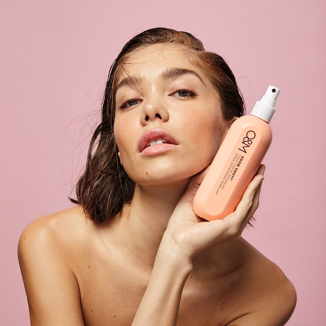 model holding a bottle of O&M Know Knott to her face