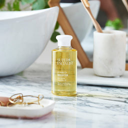 Vitamin C cleansing oil bottle in bathroom on marble table next to a sink